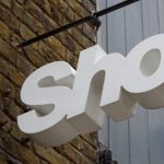 White coloured shop sign in front of a trade building